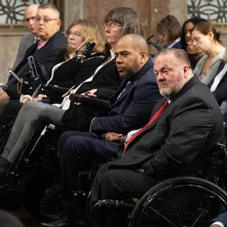 Veterans in wheelchairs seated together at a congressional advocacy hearing